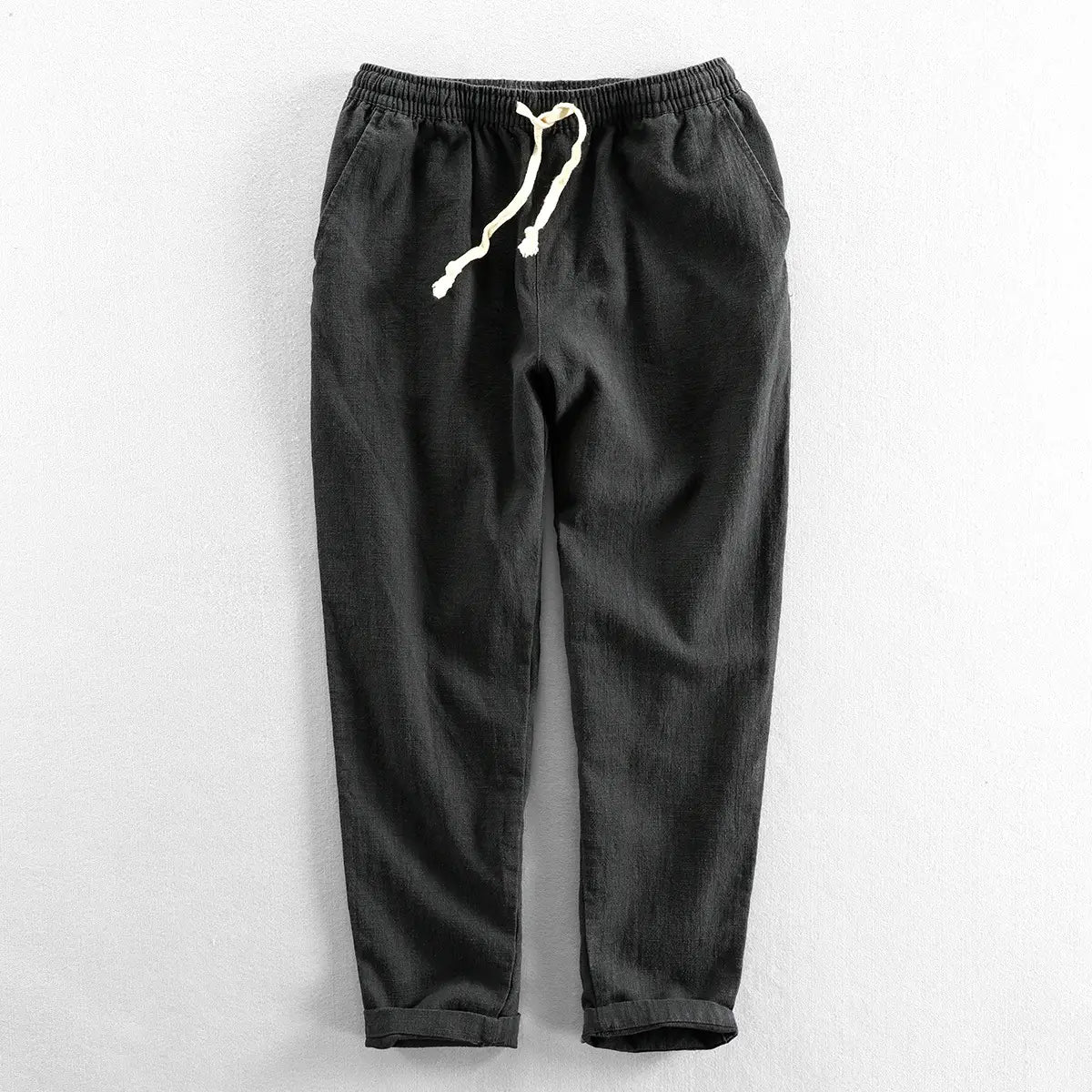 Men’s relaxed fit dark gray corduroy joggers with a white drawstring waistband and cuffed hems made of linen material.