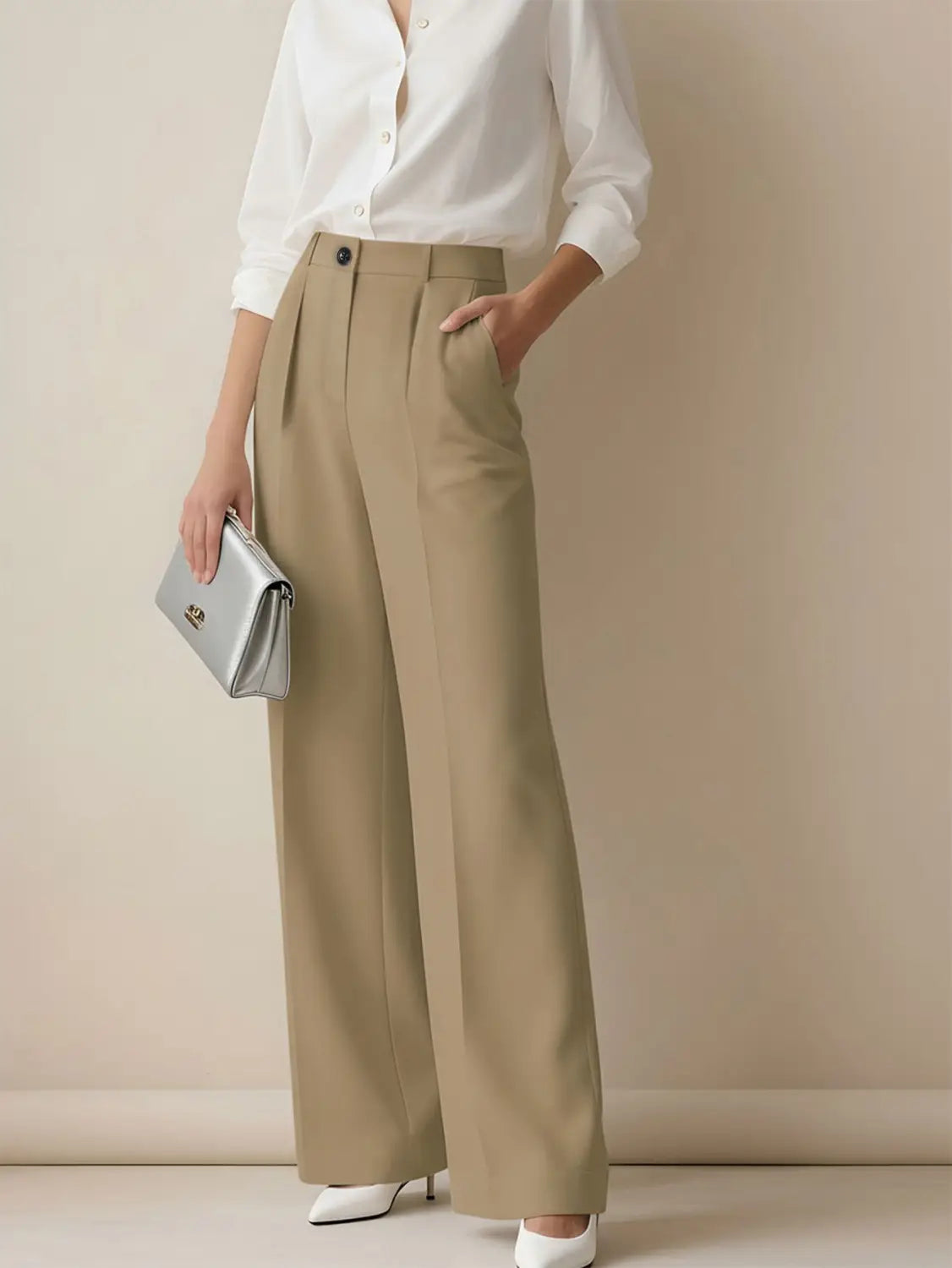 Eine elegante silberfarbene Clutch mit minimalistischem Design und dezenten goldfarbenen Beschlägen ergänzt hochgeschnittene, fallende gerade Beinform-Damenanzughosen.