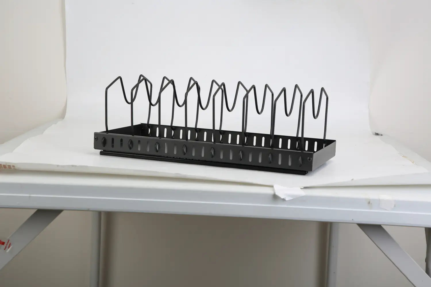 Black metal wire rack pull out pots and pans organizer with wavy vertical supports perforated base and 8 dividers for kitchen storage.