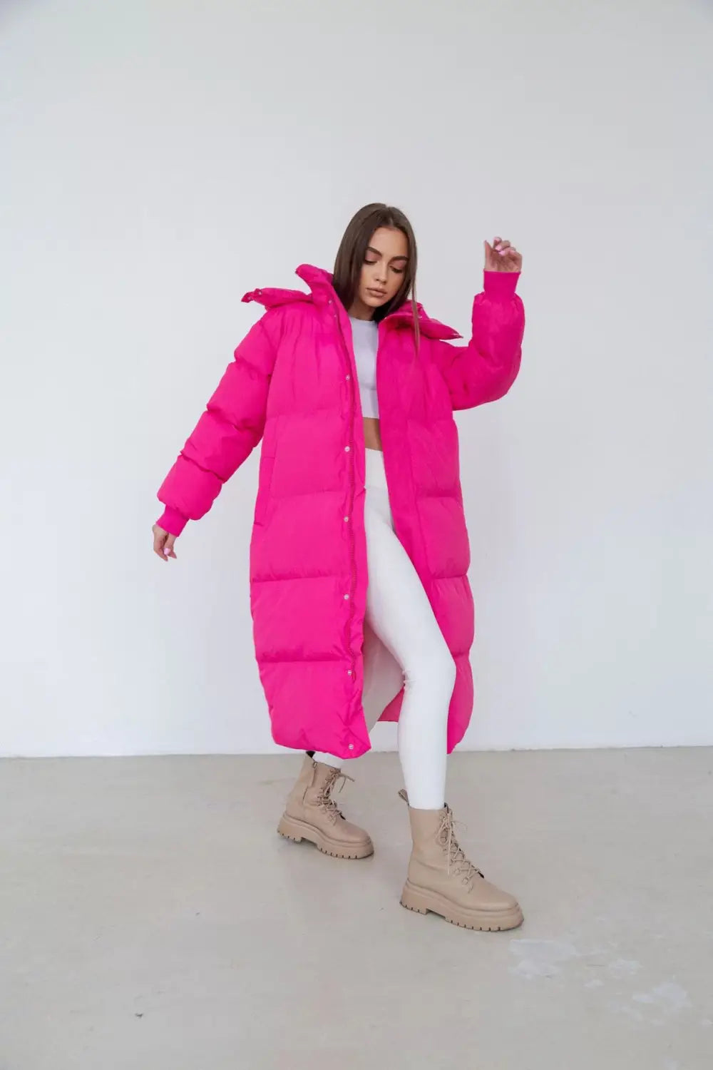Une doudoune matelassée fuchsia pour femme, avec un design matelassé et une capuche adaptée aux vêtements d’hiver.