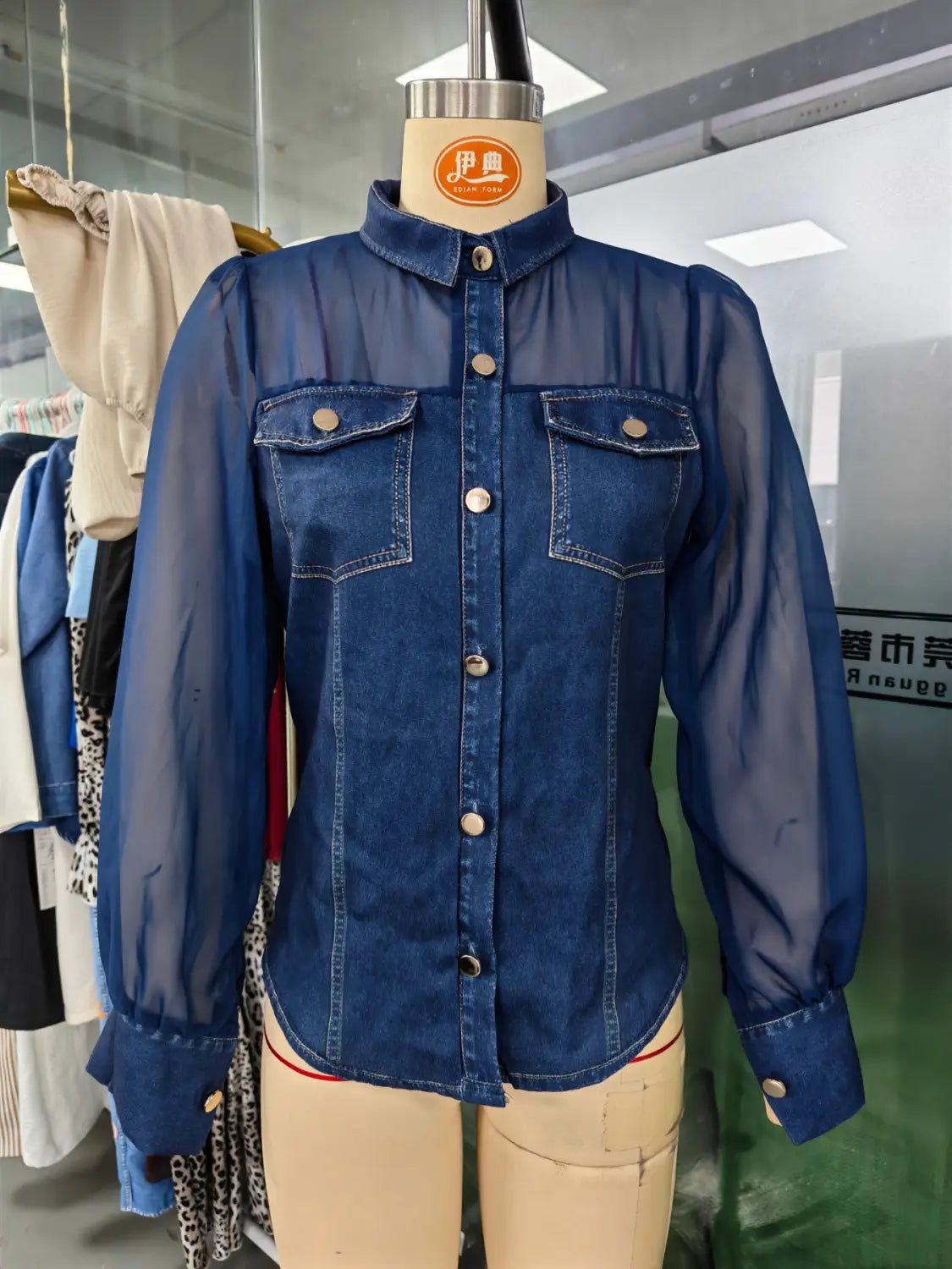 Haut à encolure en V à manches transparentes en denim bleu, comportant des manches longues transparentes et des poches avant boutonnées.