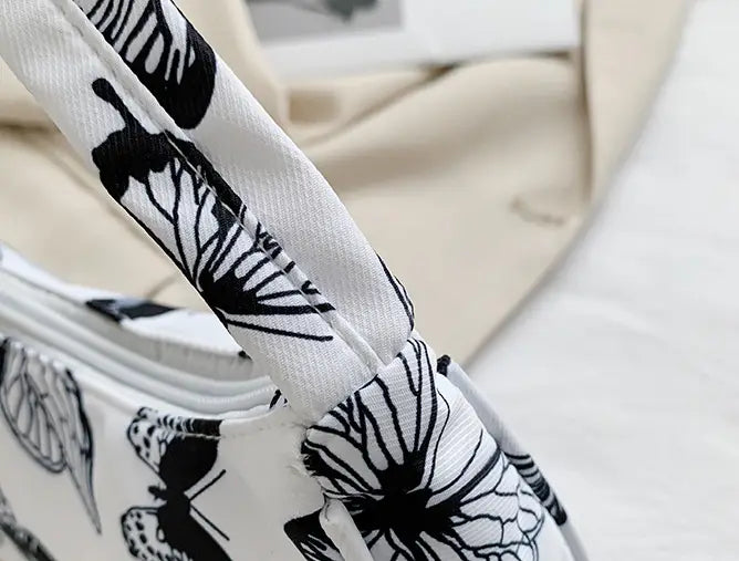 White canvas crossbody bag for women featuring black butterfly and floral prints designed as an animal print underarm shoulder bag.