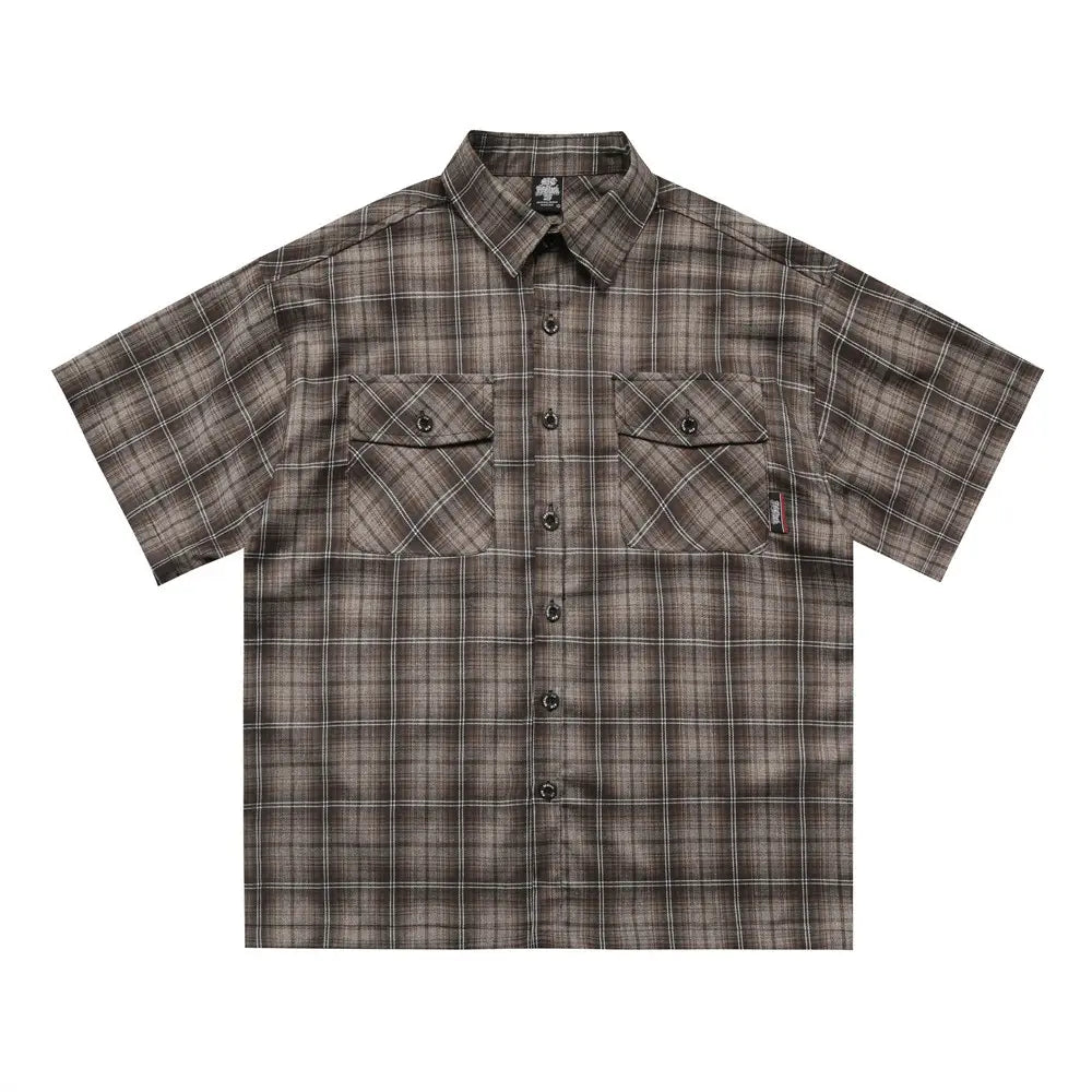A short-sleeved embroidered plaid shirt in muted brown and gray with two chest pockets and flap closures.