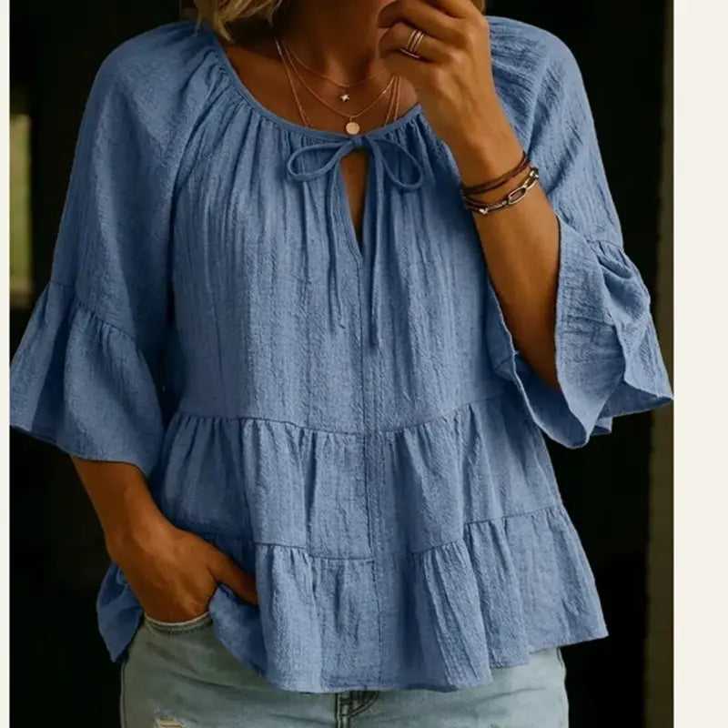 Blusa de algodón y lino color azul claro con textura, con volantes en niveles y escote con lazo al frente.
