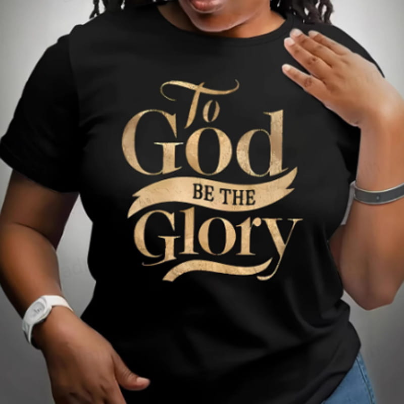 Camiseta negra de algodón con letras en pan de oro que dicen «to god be the glory» en una tipografía decorativa tipo caligrafía, para inspirarse en lo religioso.
