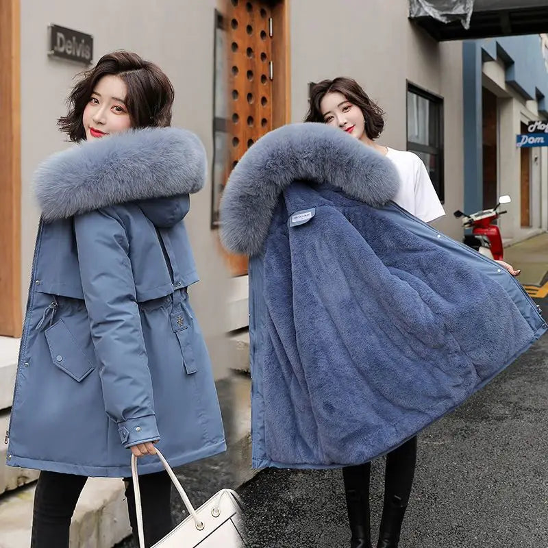 Damen Winter-Parka in mittlerer Länge in Blau mit einer plüschigen, grauen Fellverbrämung an der Kapuze und einer gesteppten Innenfütterung, ausgelegt für kaltes Wetter.