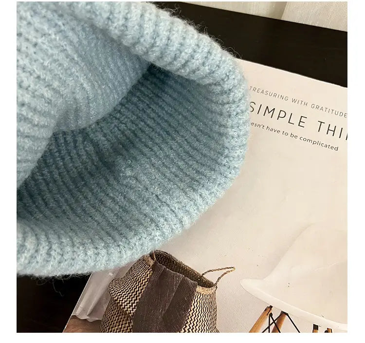 A soft light blue knitted beanie hat with cat embroidery ribbed texture and a slightly fuzzy edge.