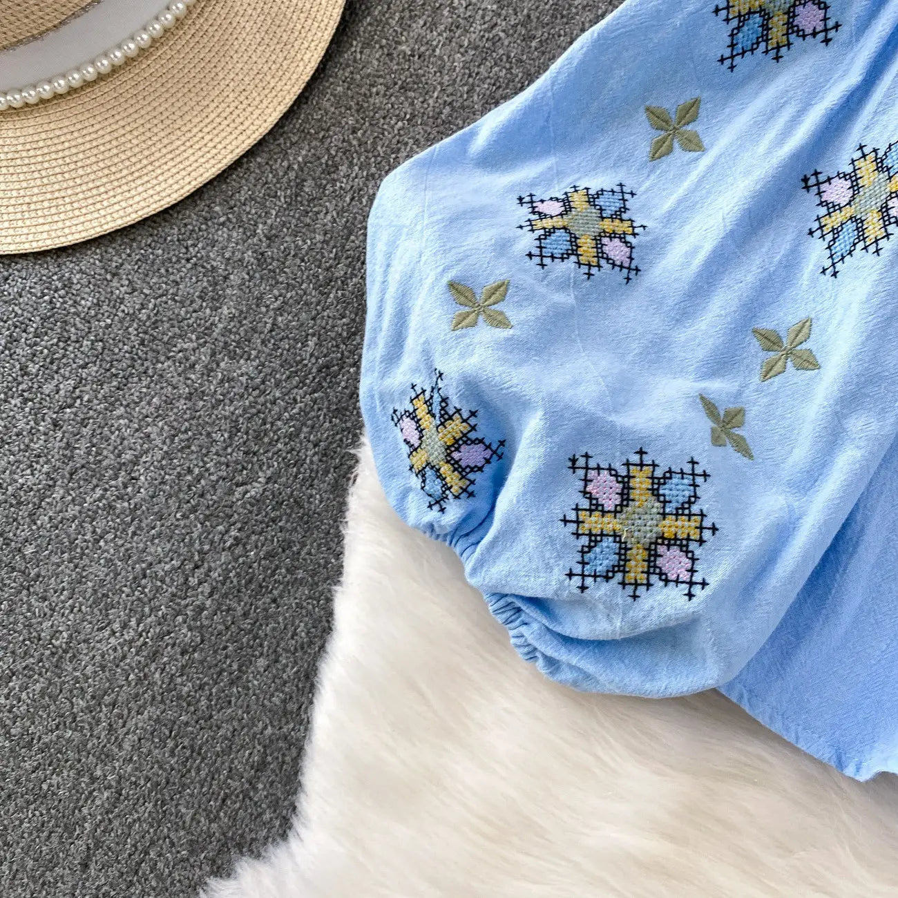 Light blue cotton shorts featuring colorful cross-stitch embroidery with yellow pink and black patterns paired with an embroidered lantern sleeve tie neck blouse.