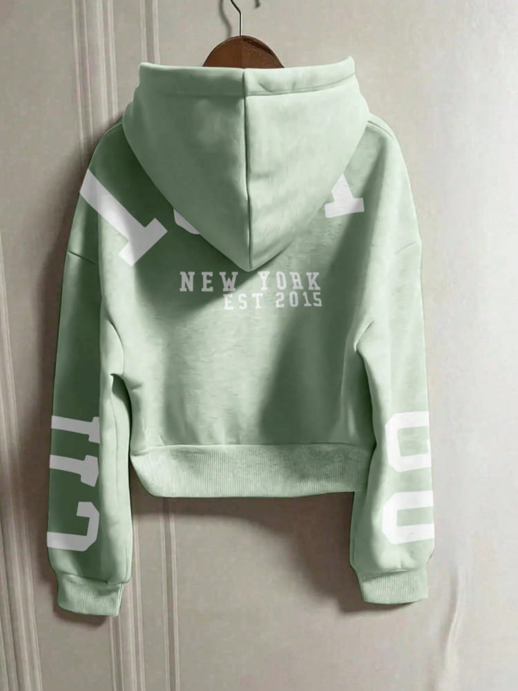 Hoodie court vert menthe avec lettrage blanc « New York Est 2015 » et graphiques géométriques audacieux au dos, partie de la collection de sweat-shirts à capuche zippés imprimés graphiques.