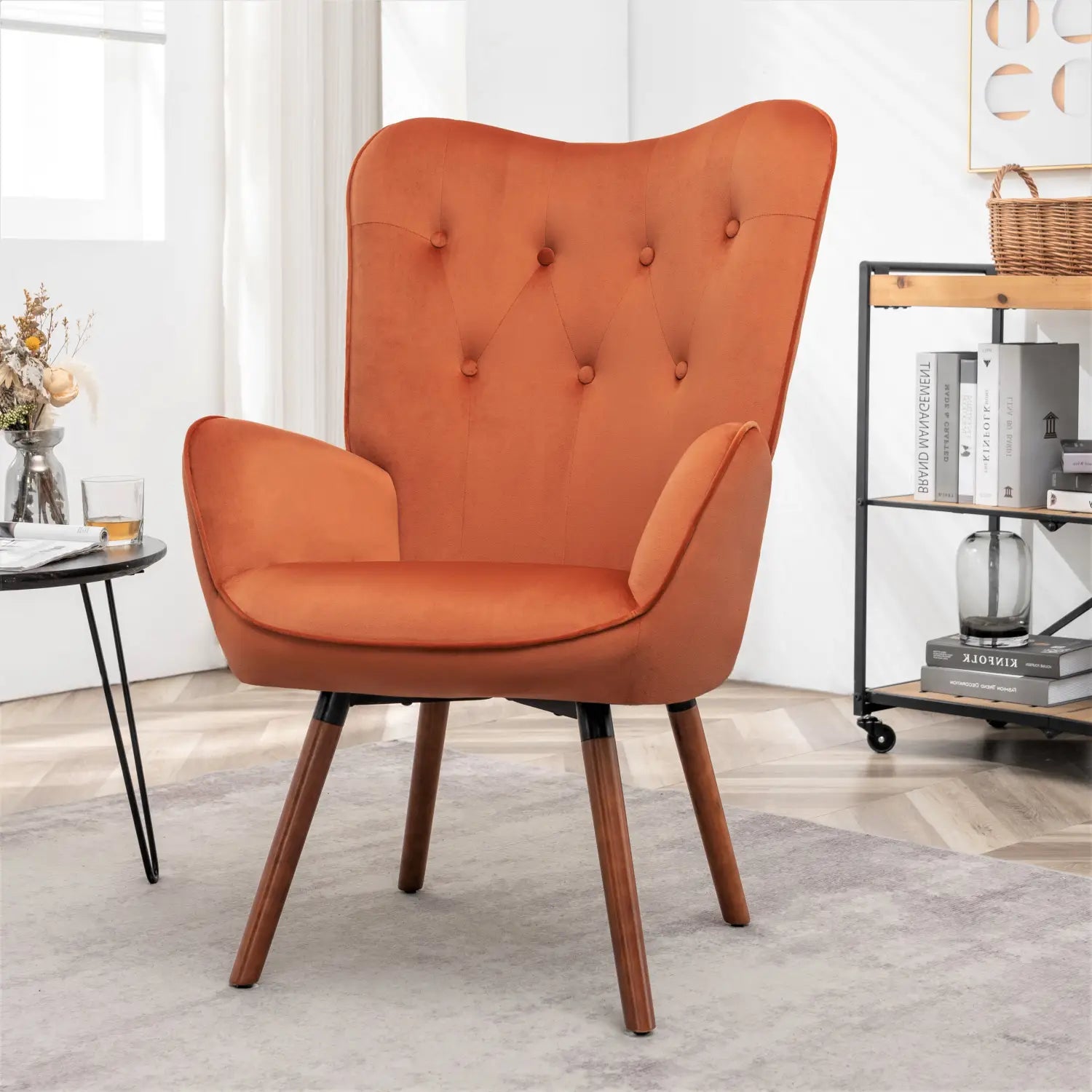 Una silla de acento tipo wingback de estilo moderno de mediados de siglo con tapizado acolchado con capitoné color naranja y patas de madera.