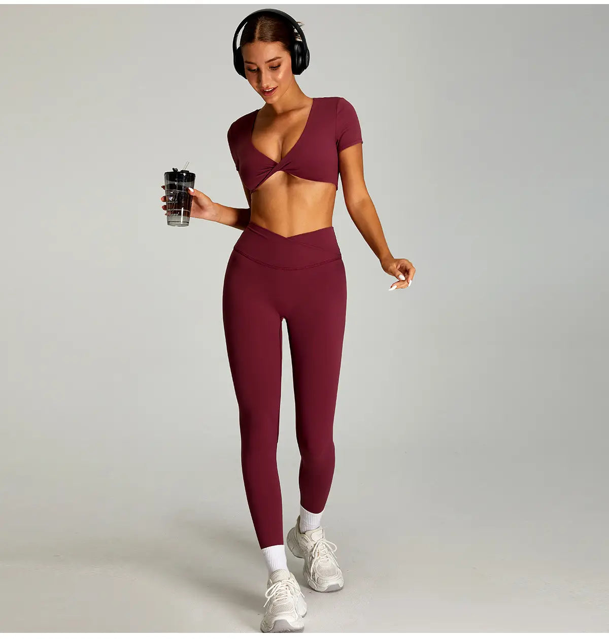 Ensemble de sport bordeaux à deux pièces, avec un haut court torsadé à l’avant et des leggings de sport taille haute à séchage rapide, idéal pour les activités de fitness.