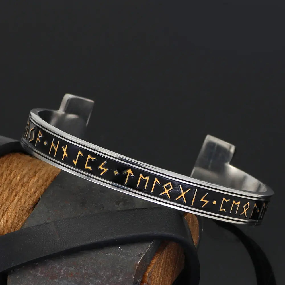 Adjustable Viking rune open cuff bracelet made of silver titanium steel with black inlay and gold-colored Norse runes.