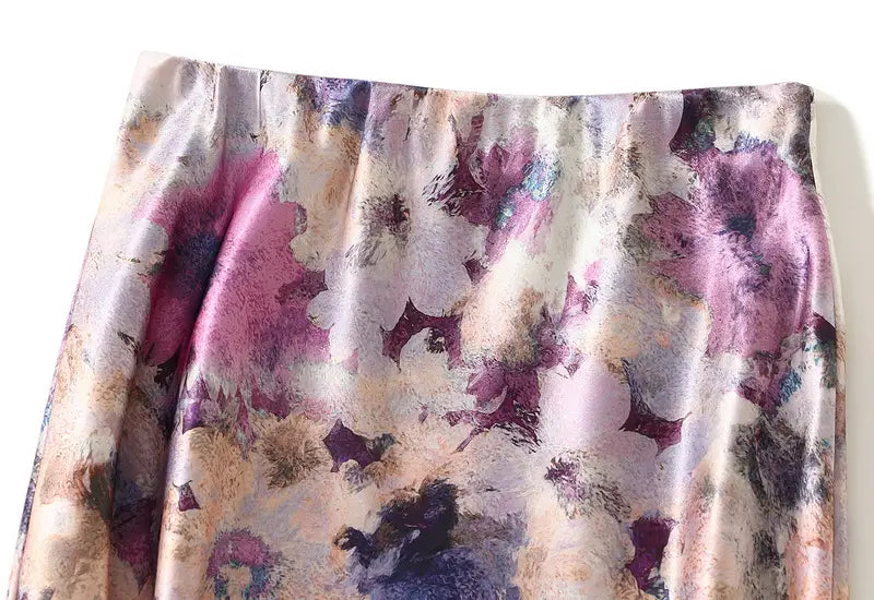 Ein fließender Satin-Floral-Midirock mit hoher Taille mit einem sanften Aquarellstil-Muster in Tönen von Mauve, Lavendel und staubigem Rosenholz.