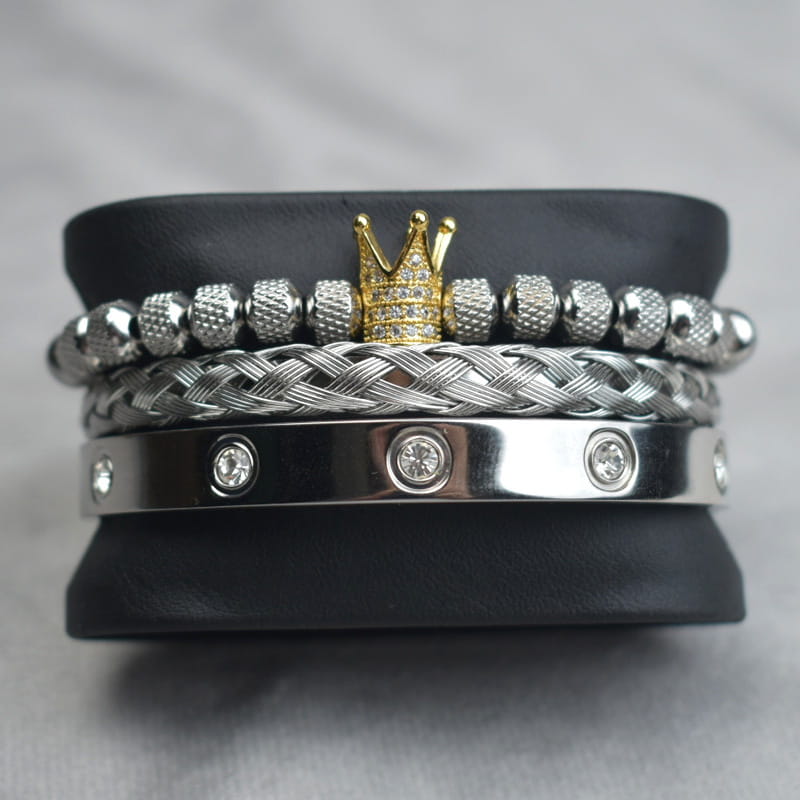 Stacked silver and gold crown-themed bracelets featuring textured beads, braided metal links, and a sleek stainless steel band with embedded crystals in the Crown Royal Diamond Beaded Bracelet Set with Braided Bands.