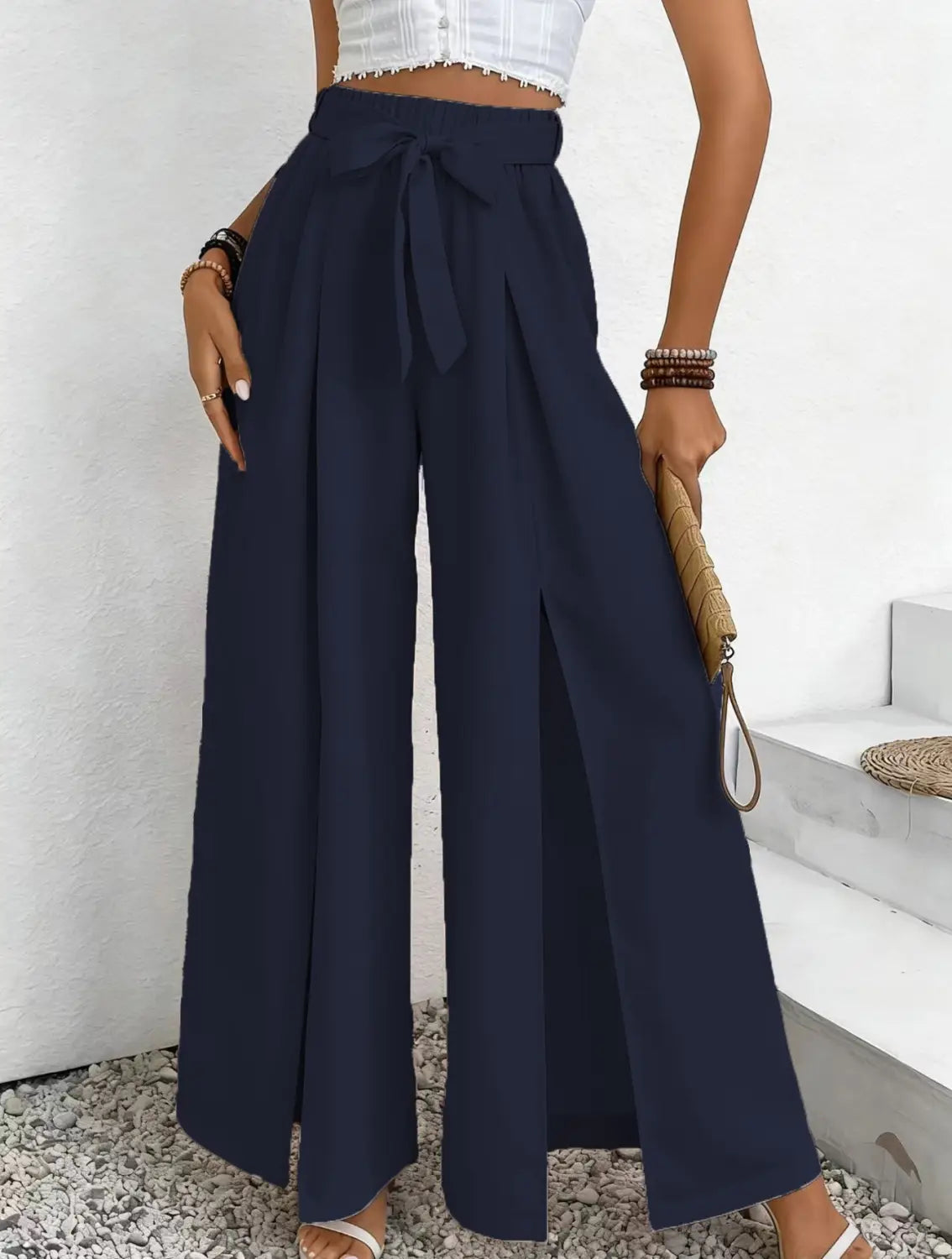 Pantalon ample à taille haute bleu marine, avec une ceinture à nouer et une fente avant, conçu comme un pantalon ample et décontracté.