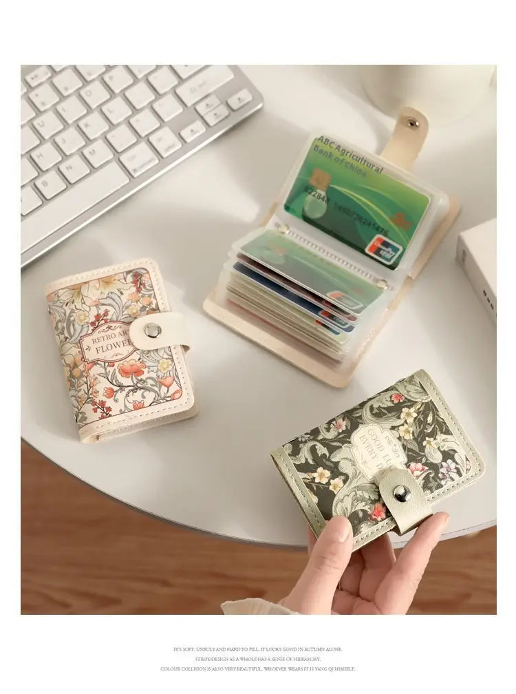 A hand holds a compact dark green vintage floral leather card holder wallet with silver toned hardware and a decorative clasp.