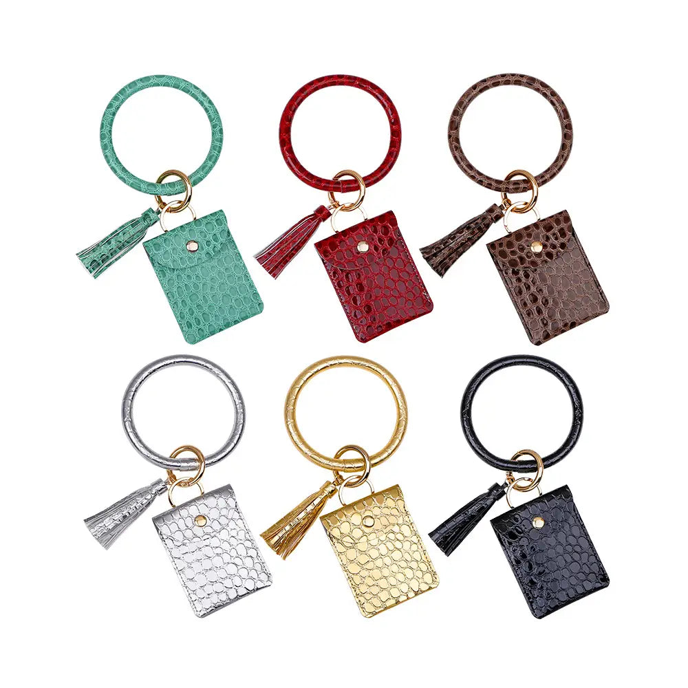Lot de six porte-cartes avec mousqueton de poignet en cuir, avec gland, présentant un motif de crocodile dans des couleurs assorties, notamment bleu-vert, rouge, brun, argent, or et noir.