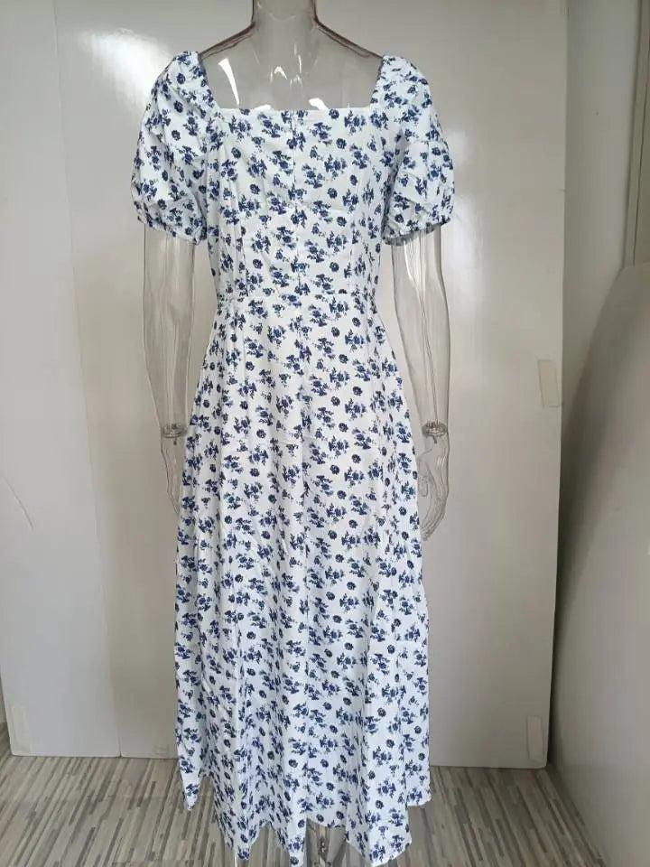 White midi dress with navy blue floral pattern featuring puff sleeve and square neck design.