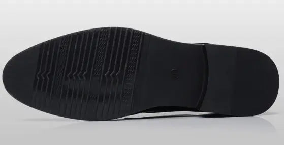The back side of a black rubber shoe sole with a textured ribbed pattern and smooth heel section on men’s brown leather formal dress shoes.
