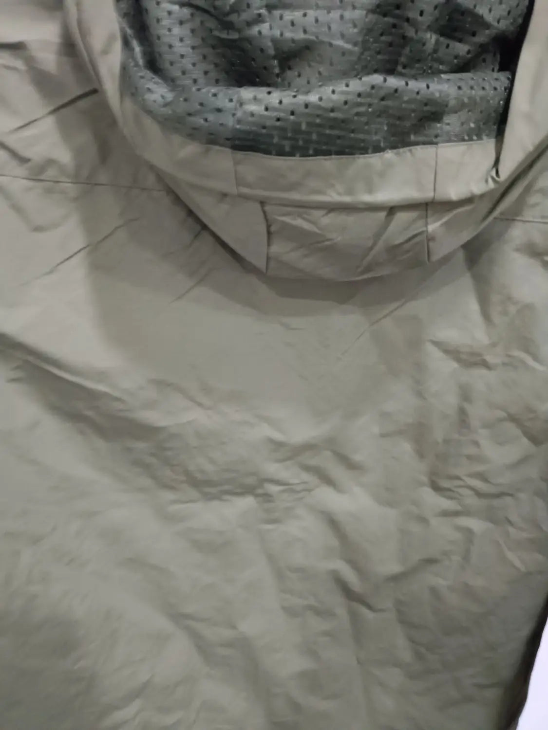 Chaqueta de senderismo con capucha impermeable color beige, con forro interior perforado gris y costuras reforzadas.
