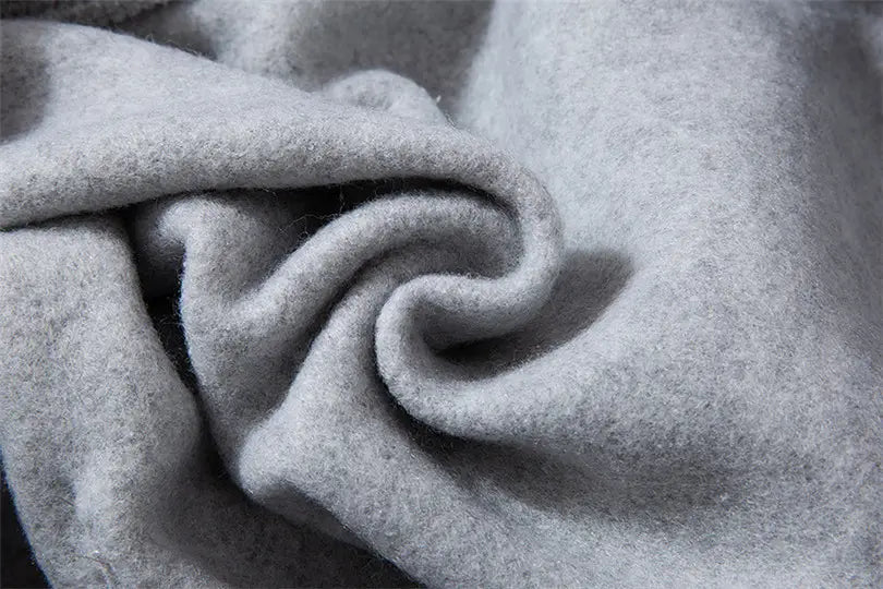 Tissu de laine gris clair et doux, avec une surface texturée moelleuse, présenté sur le sweat à capuche de type pullover « Philippiens 4 13 » avec visuel croisé.