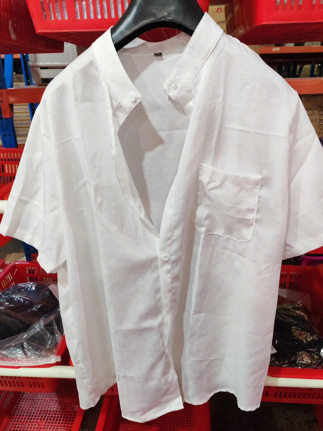 White short-sleeved casual shirt with a mandarin collar, button-up front, and chest pocket hanging on a black hanger