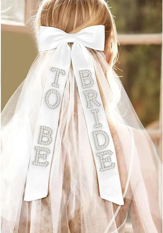 white satin bridal bow veil with rhinestone to be bride lettering attached to a sheer veil