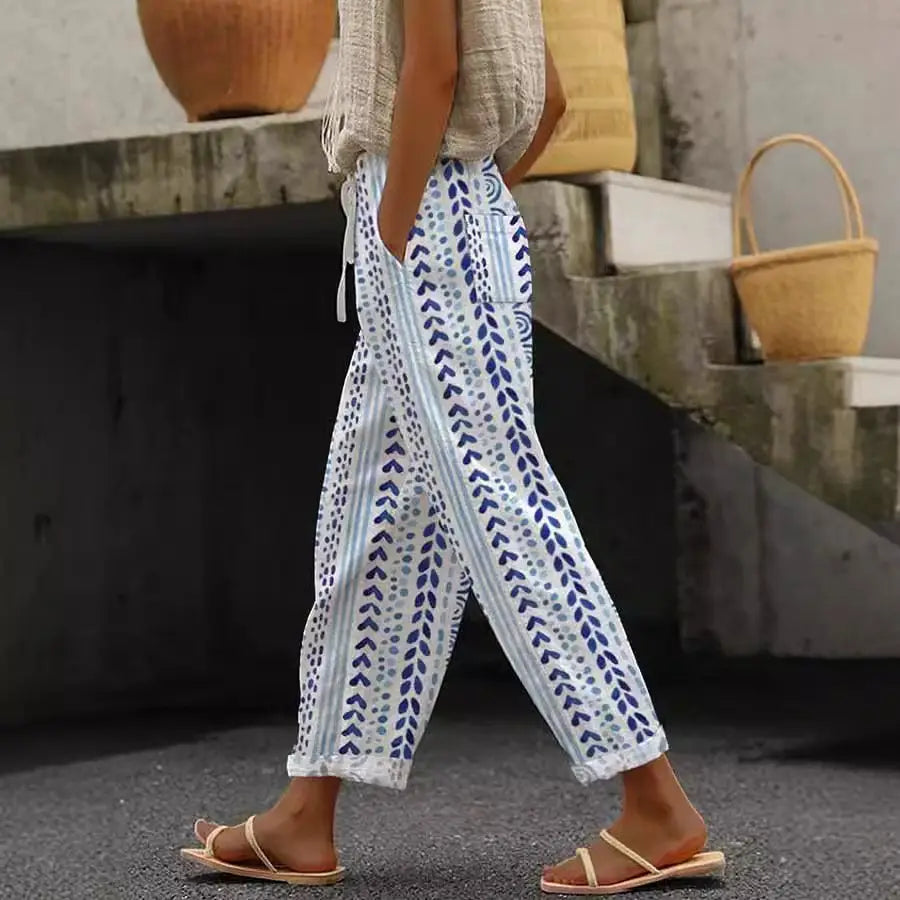White cotton casual patterned drawstring pocket trousers with blue leafy patterns, light gray vertical stripes, and rolled cuffs.