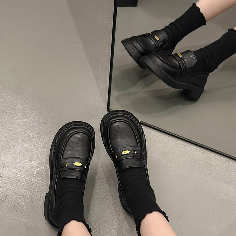 black leather loafers with gold-tone buckle accents featuring a classic design.