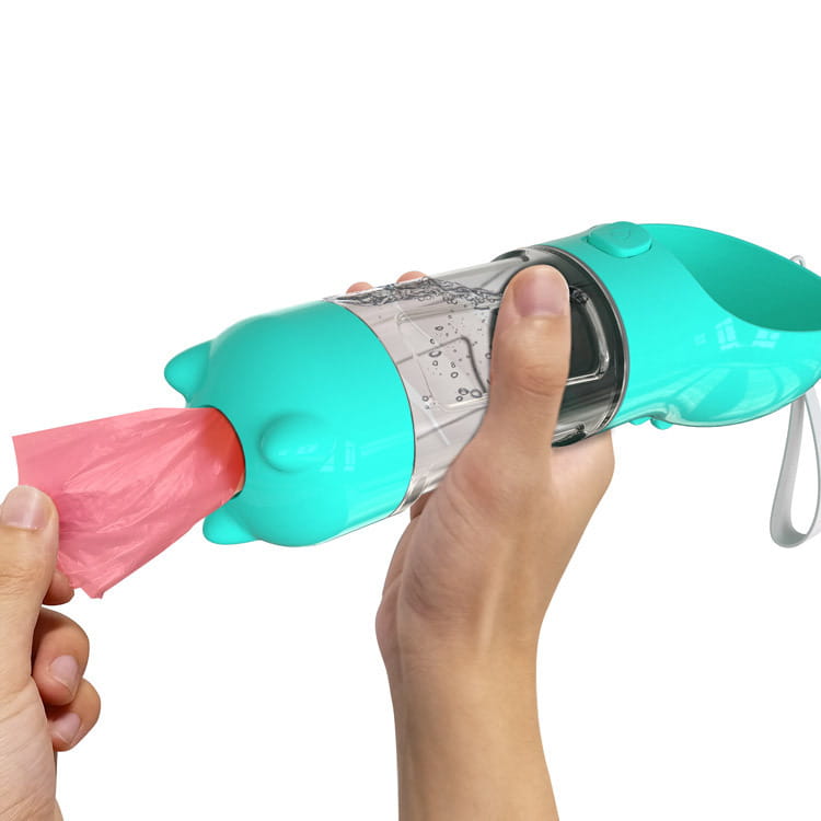 Bouteille d’eau multifonctionnelle pour chien en plastique turquoise, avec une section transparente et un distributeur de sacs à crottes rose fixé.