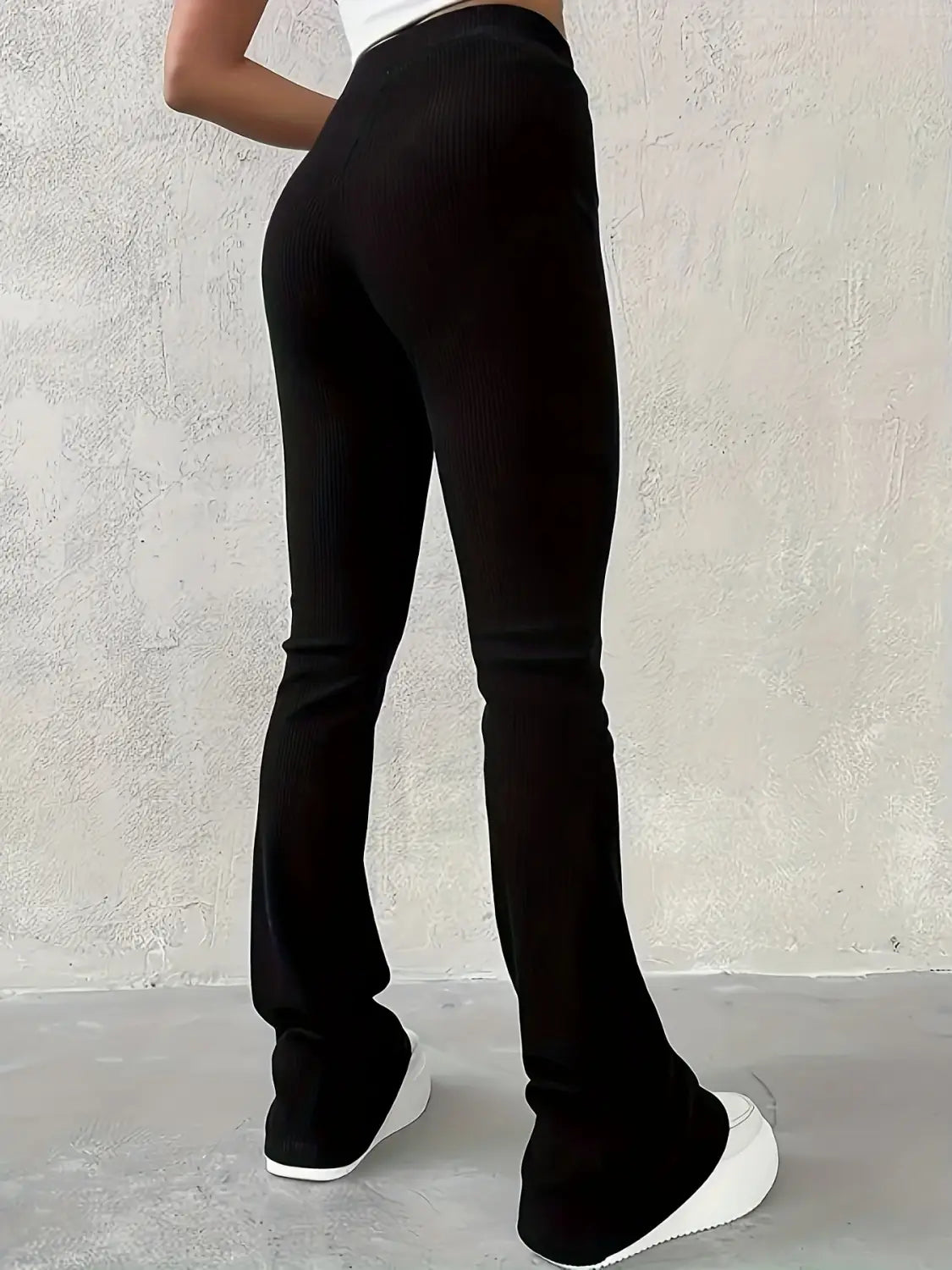 Schwarze hoch geschnittene Ripp-Flared-Leggings aus elastischem Stoff mit Rückansicht.