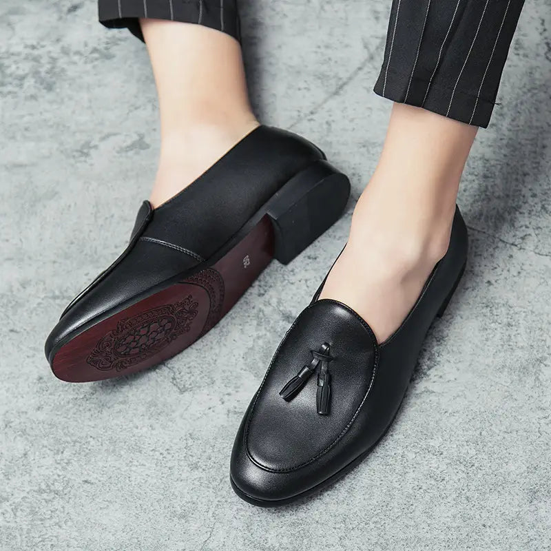 Mocassins en cuir noir à glands britanniques pour jeunes hommes, présentant un détail de gland à l’avant.