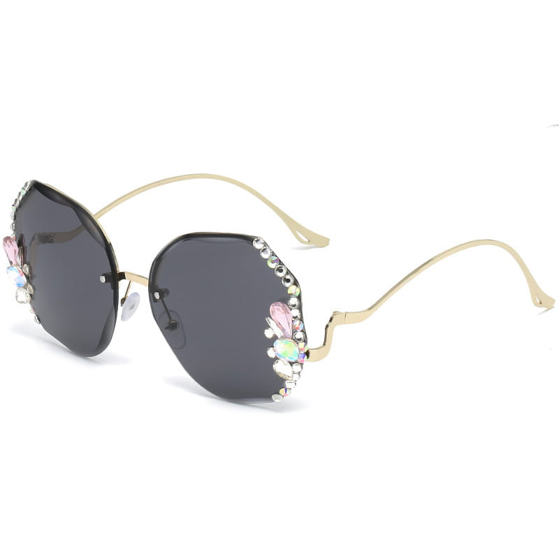 Las gafas de sol de lujo con pedrería de mariposa tipo cristal y protección UV400 presentan monturas doradas con lentes color gris oscuro y adornos decorativos de gemas rosadas y transparentes a lo largo de los bordes exteriores.
