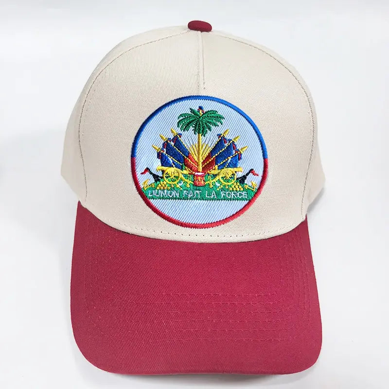 Beige and maroon baseball cap featuring an embroidered circular patch of the Haitian national emblem with a palm tree cannons and the motto union fait la force designed for sun protection.