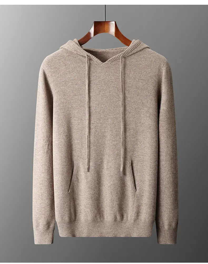 Sudadera con capucha de punto de cachemir beige para hombre, con cordones y bolsillos delanteros colgados en una percha de madera, diseñada como jersey holgado de invierno para hombre.