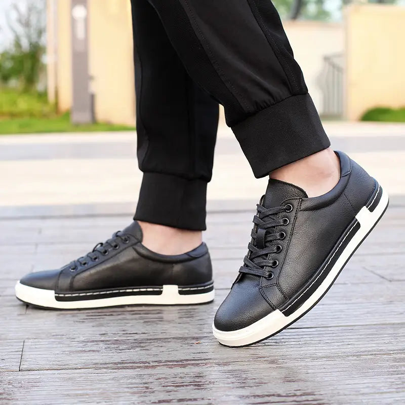Les baskets basses en cuir pour homme, faites à la main, de couleur noire, avec des semelles en caoutchouc blanc et des coutures contrastantes, pour un usage décontracté.