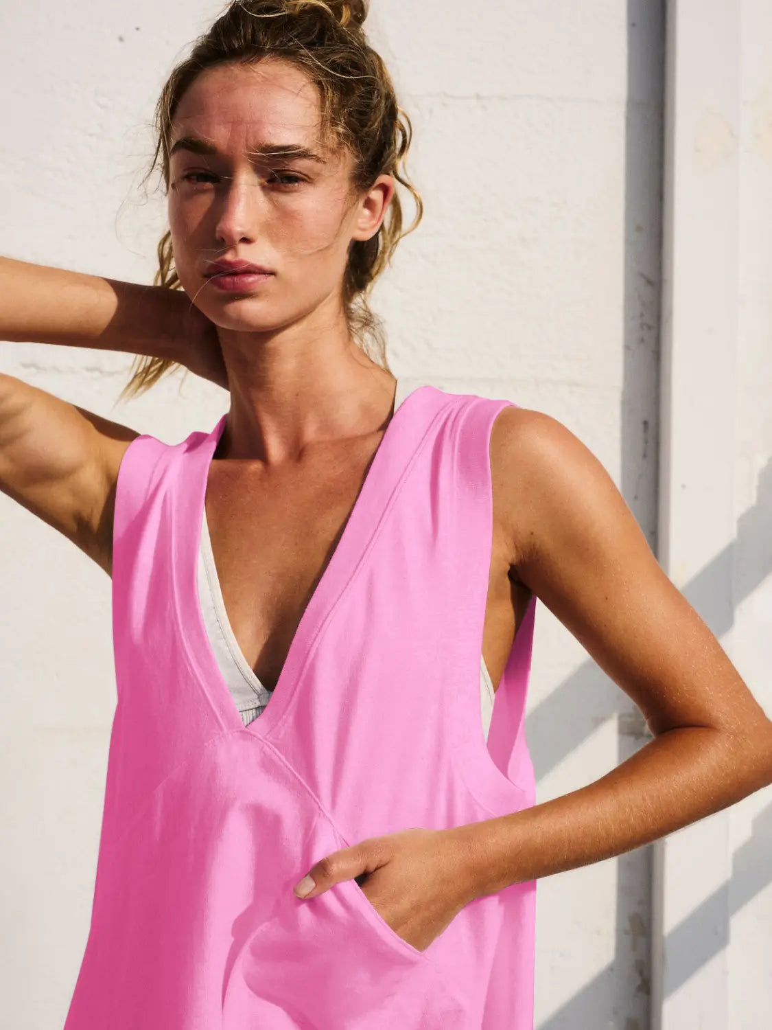 A vibrant pink sleeveless cotton wrap vest top with a relaxed fit deep v neck and cut-out shoulder details.