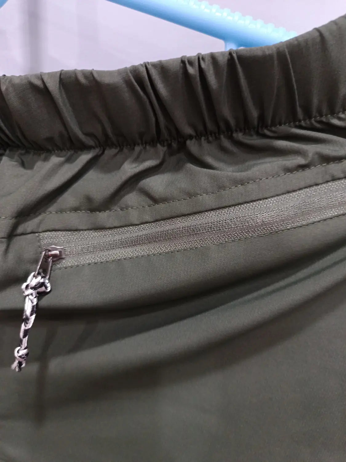 olive green nylon convertible tactical hiking shorts with silver zipper and chain pull detail