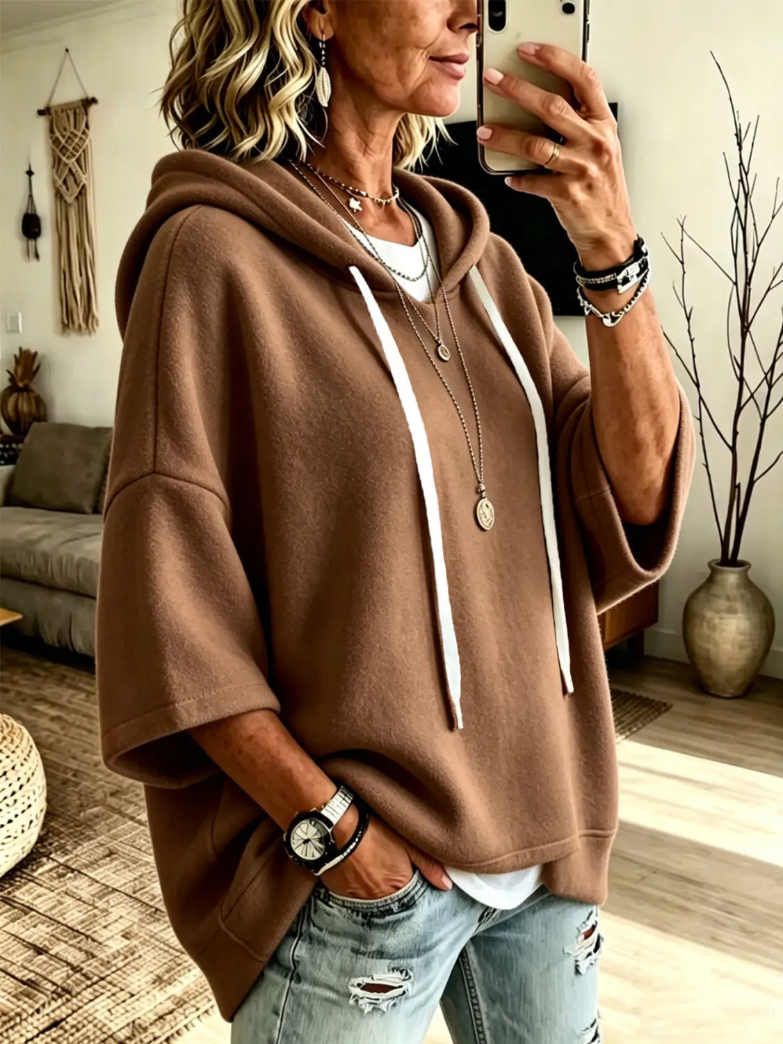 A cozy oversized fleece hooded top in brown with white drawstrings and three-quarter sleeves made of soft material.