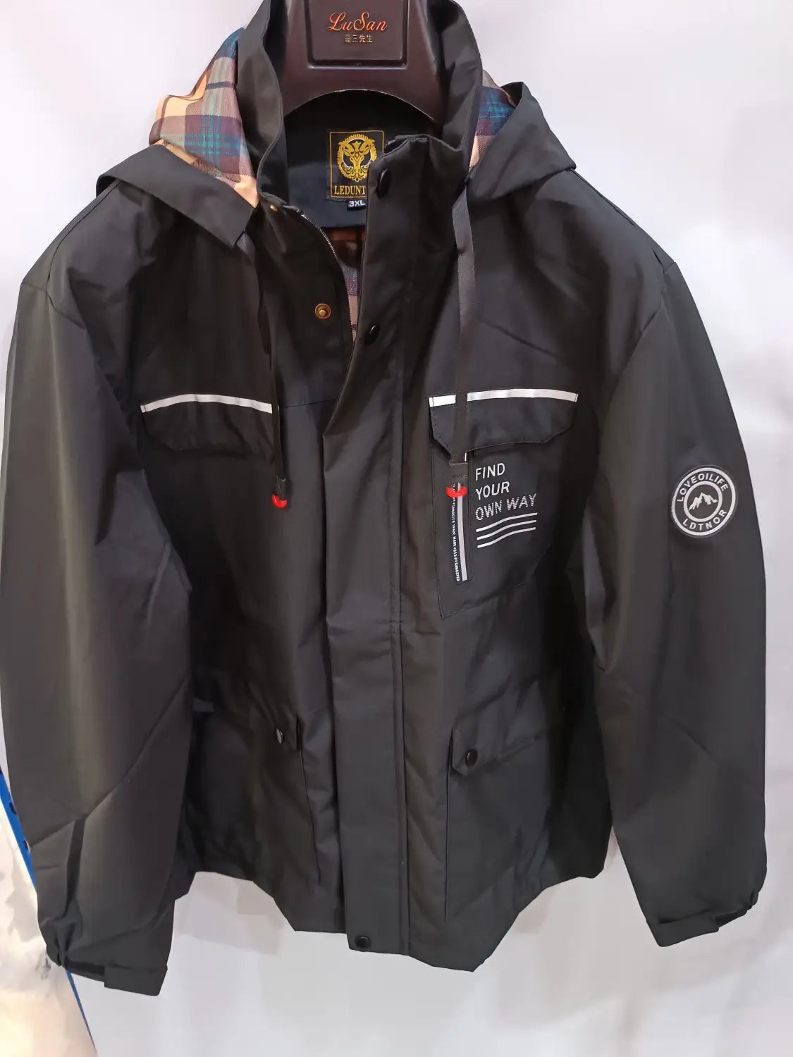 Men winter hooded parka coat in black waterproof material with plaid lining white stripe accents and a find your own way patch on the chest.