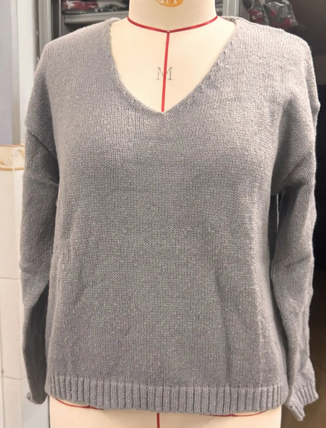 Grauer Strickpullover mit V-Ausschnitt und überschnittener Schulterpartie, mit gerippten Bündchen und Saum.