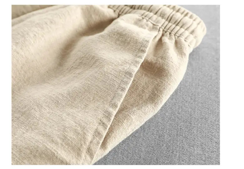 Beige linen trousers with an elastic waistband designed as men’s relaxed fit drawstring linen joggers.
