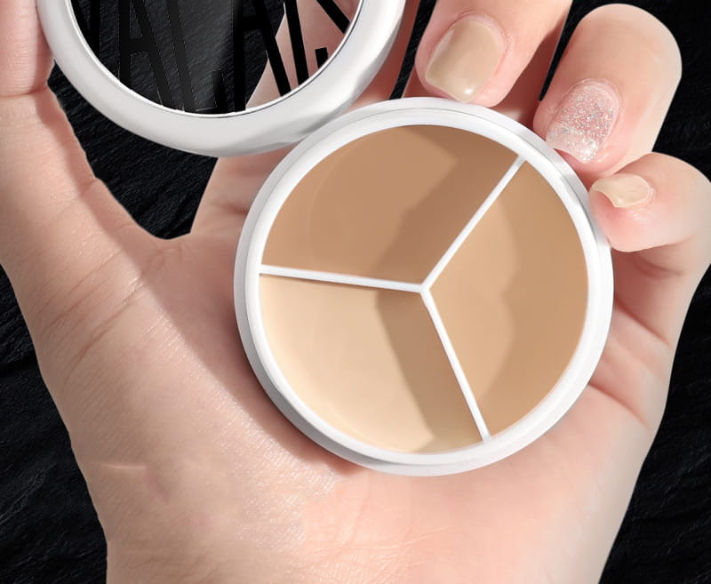 White round compact three-color concealer palette with three distinct beige-toned shades separated by white dividers and accompanying pro 270 brush.