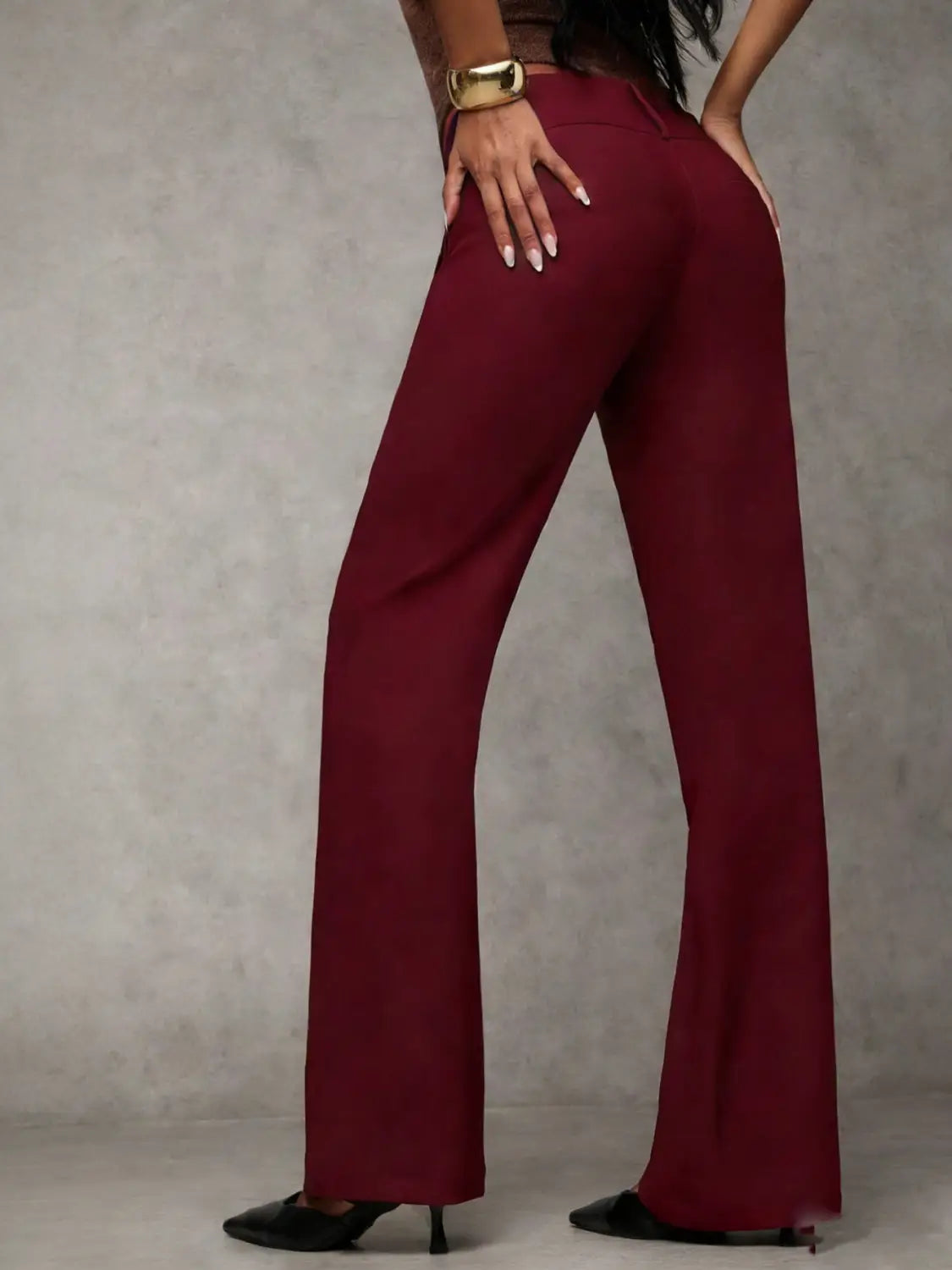 A pair of wide leg work pants in maroon featuring a high waist, smooth tailored fabric, and subtle creasing along the seams ideal for casual wear.