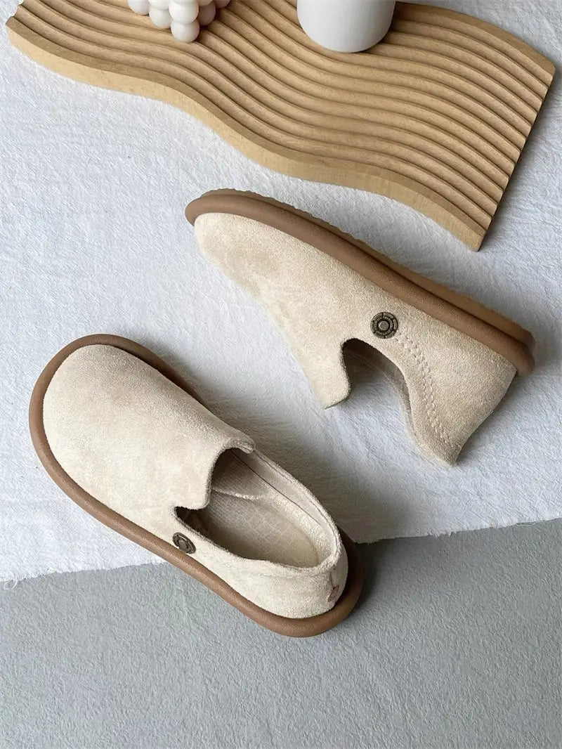 Elfenbeinfarbene Veloursleder-Slipper mit niedrigem Vintage-British-Stil-Absatz mit einer massiven braunen Gummisohle und dezenten metallisch wirkenden Knopfdetaillierungen.