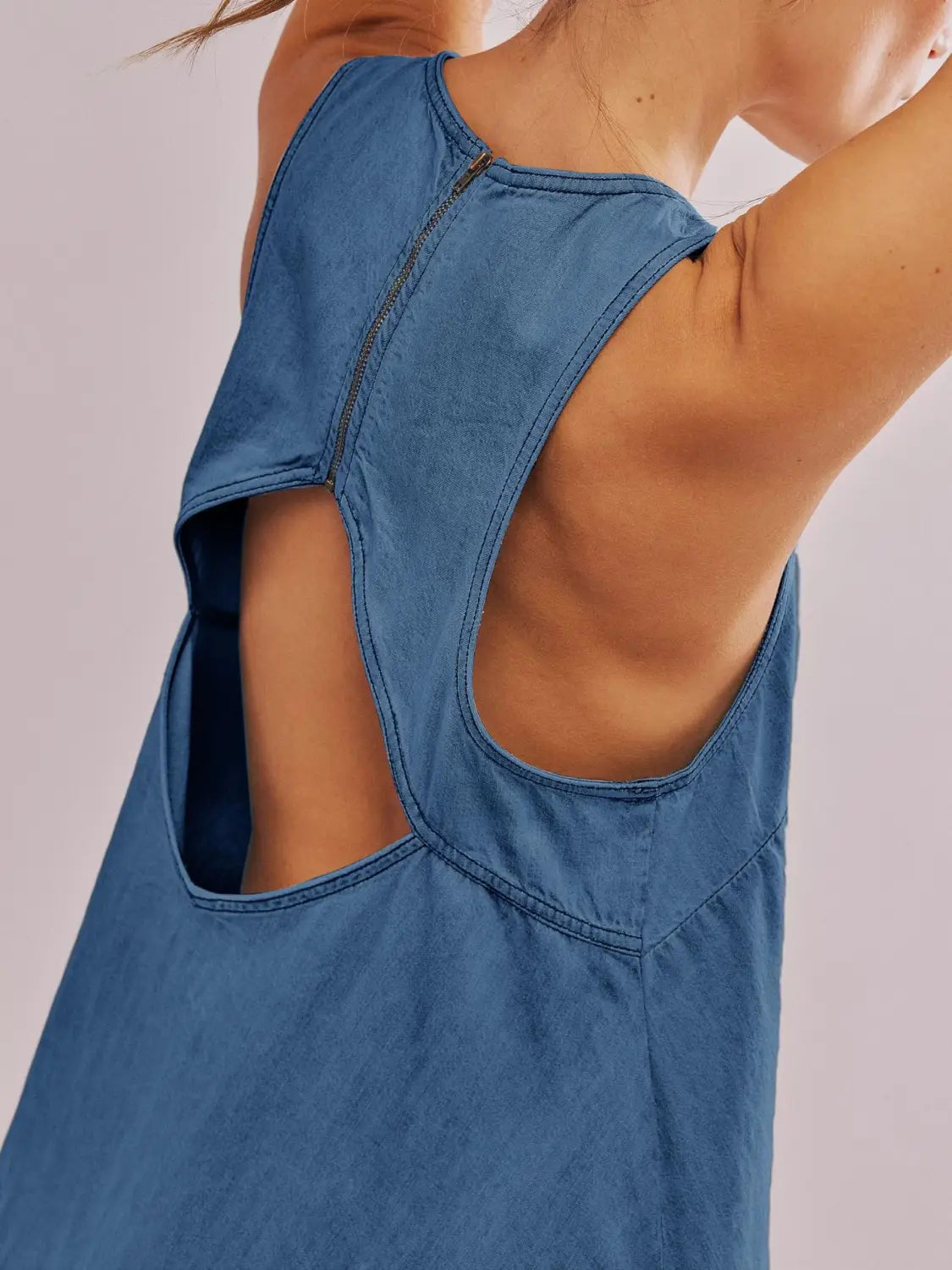 Rückansicht eines blauen Jeans-Minikleids mit hinten offenem Schleifen-Detail und Detailverschluss mit Reißverschluss