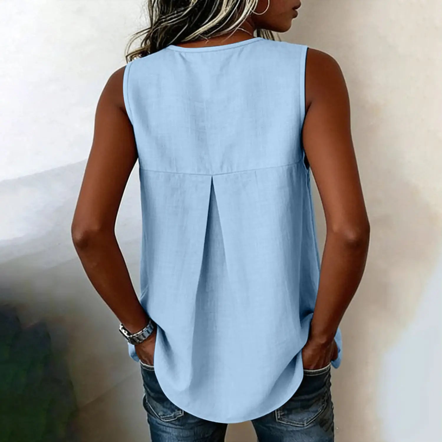 light blue sleeveless tie side button down blouse shown from the back with a relaxed fit and subtle pleating.