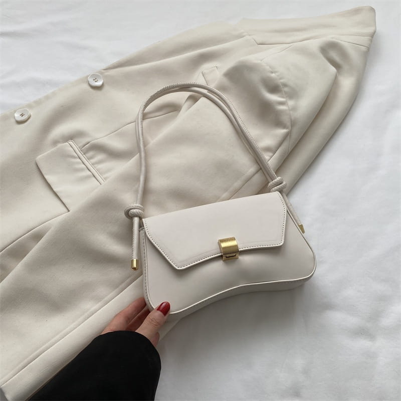 Minimalist faux leather structured shoulder bag in off-white featuring a sleek design with a gold-tone rectangular clasp and braided strap.