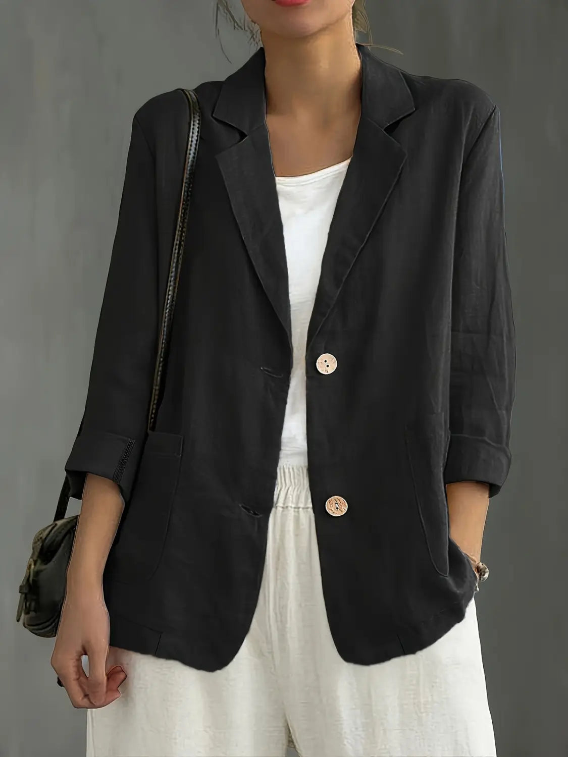 Blazer de lino para mujer, de trabajo casual, en color negro, con botones rosa claro y mangas remangadas.