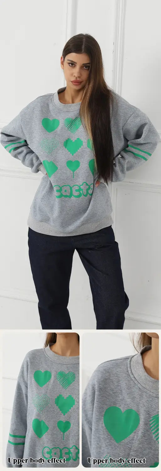 Gray oversized sweatshirt featuring green heart graphics and striped cuffs made from soft cotton blend material.